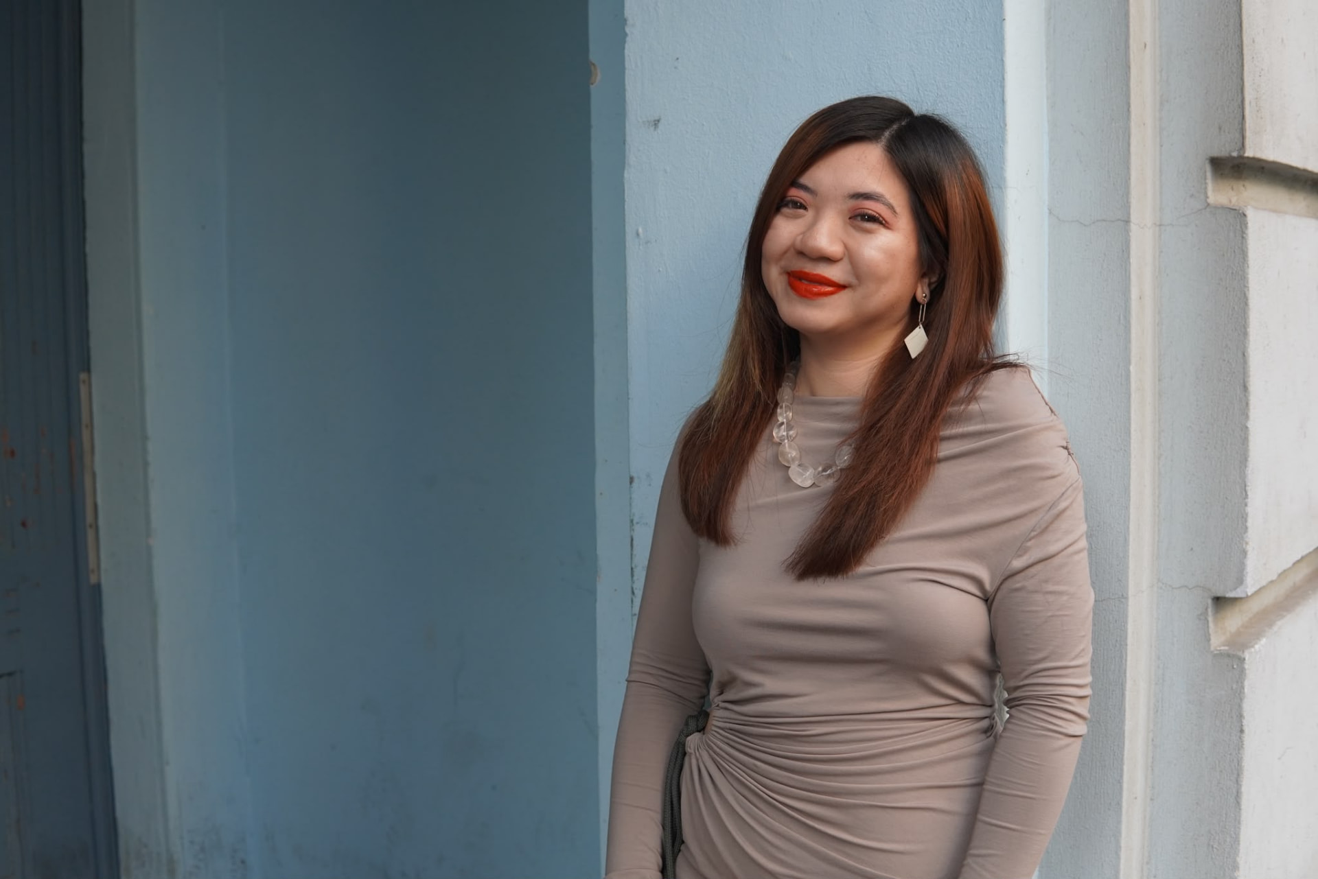 Bao Ngoc Cao lächelt vor einer blauen Hauswand